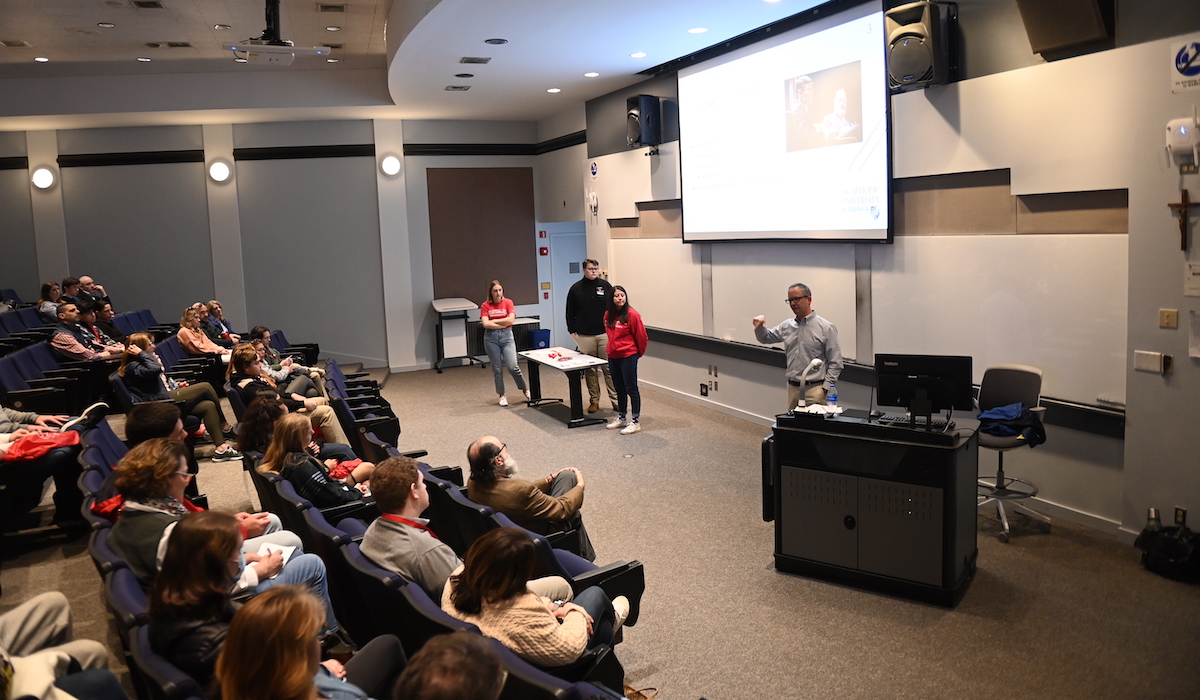 professor talking to prospective students in an auditorium