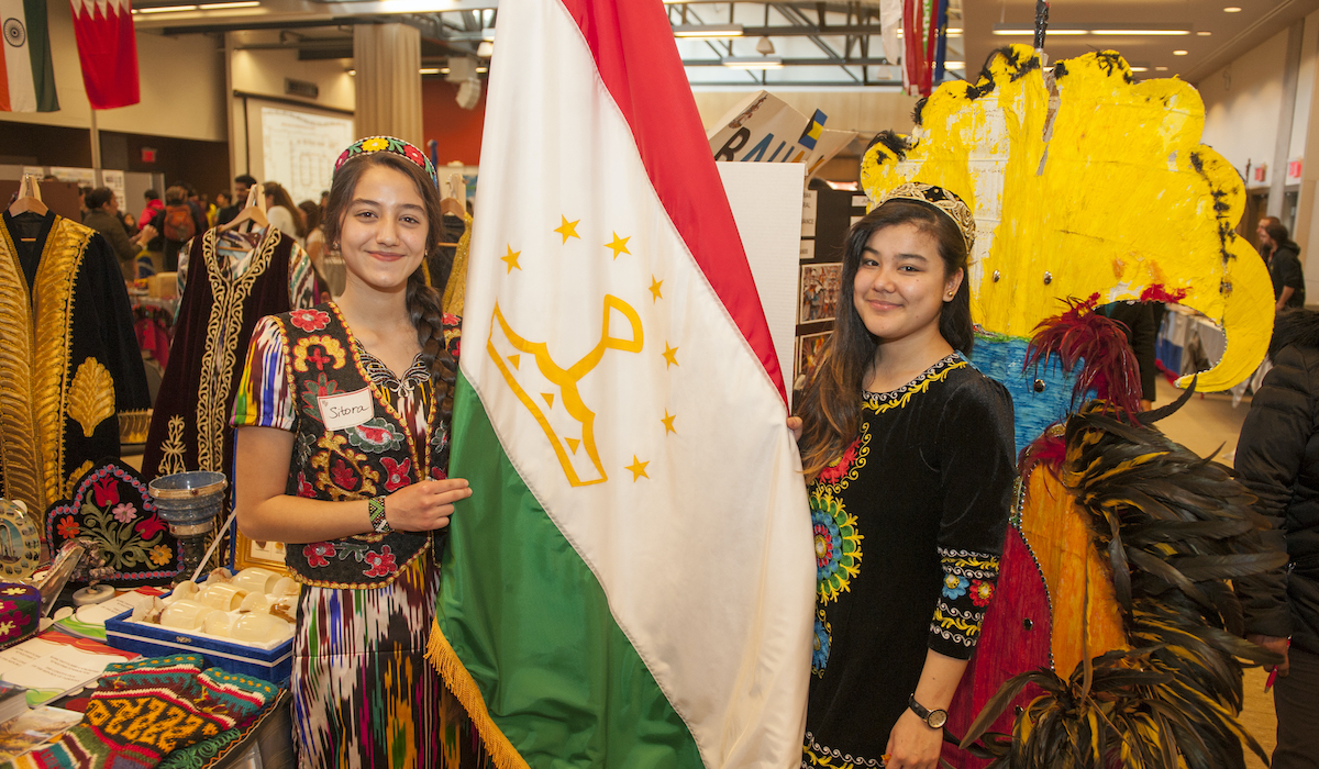 students hold the Tajikistanian flag dressed in traditional Tajikistanian attire at CUA's global fest