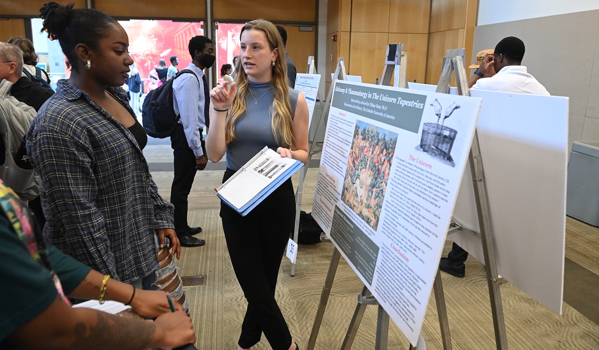 student presents her research to a fellow student at research day